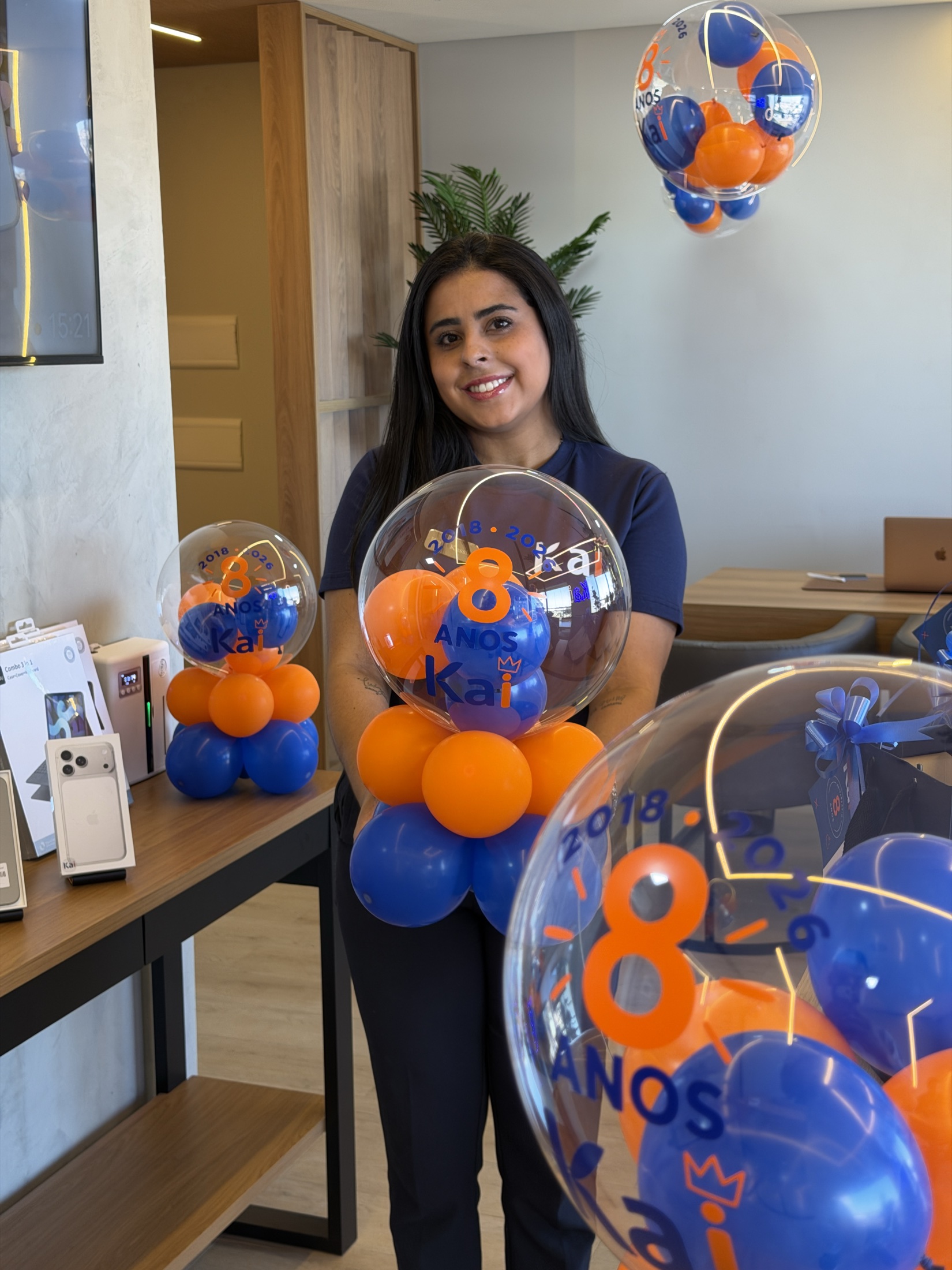 Kai segurando balões azuis e laranjas da campanha de 8 anos na loja